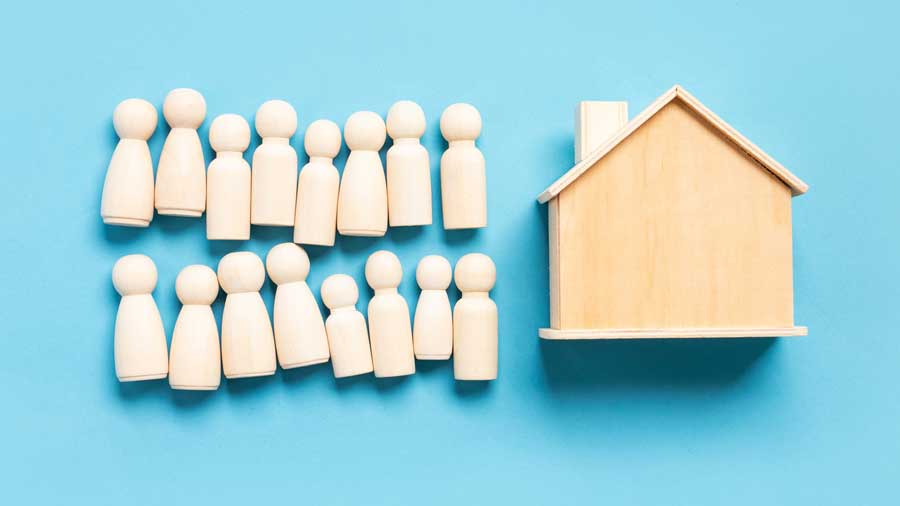 A big group of wooden people figures next to a single house 