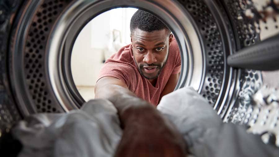 A man does loads a washing machine