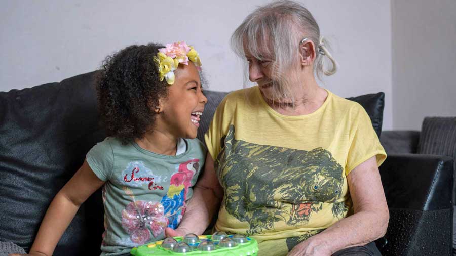 Older woman sits on the sofa with her granddaughter