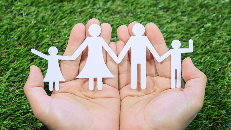 Paper silhouettes of a family rest in cupped hands