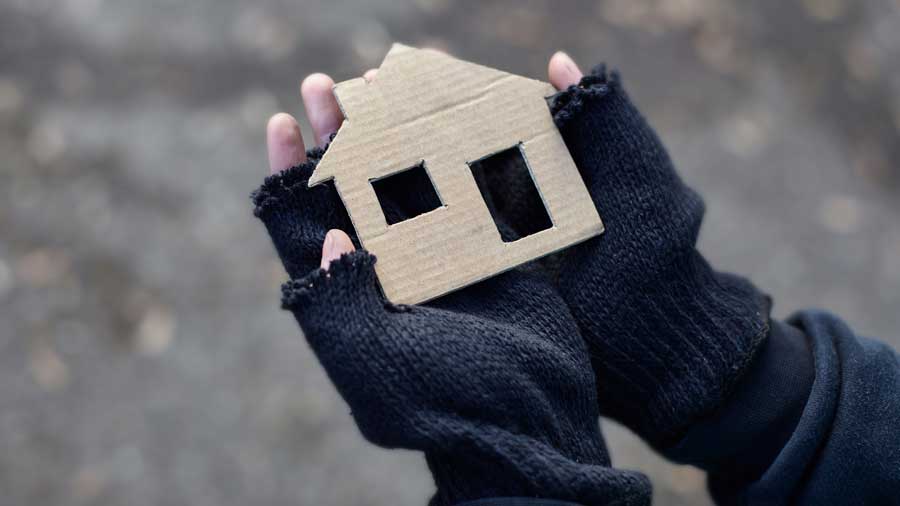 Gloved hands hold a cardboard cut-out of a house