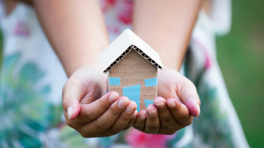 A young girl's hands holding a cardboard house