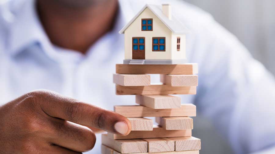 A person playing Jenga with a house balanced on top