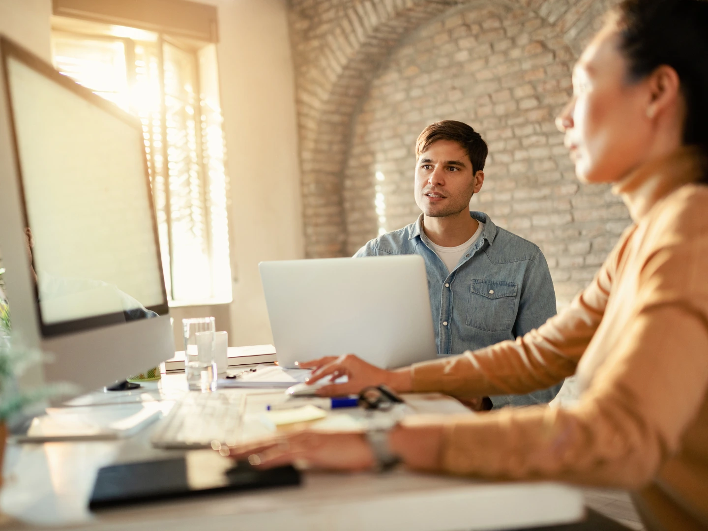 Young businessman using laptop while working with female colleague in the office. stock photo