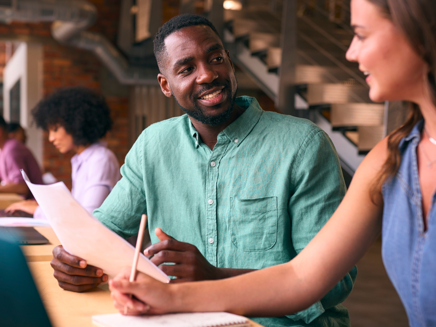 Male And Female Businesspeople Meeting In Office Discussing Documents With Colleagues In Background stock photo